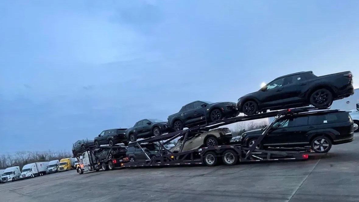 A loaded JDS car carrier on a staging lot at dusk